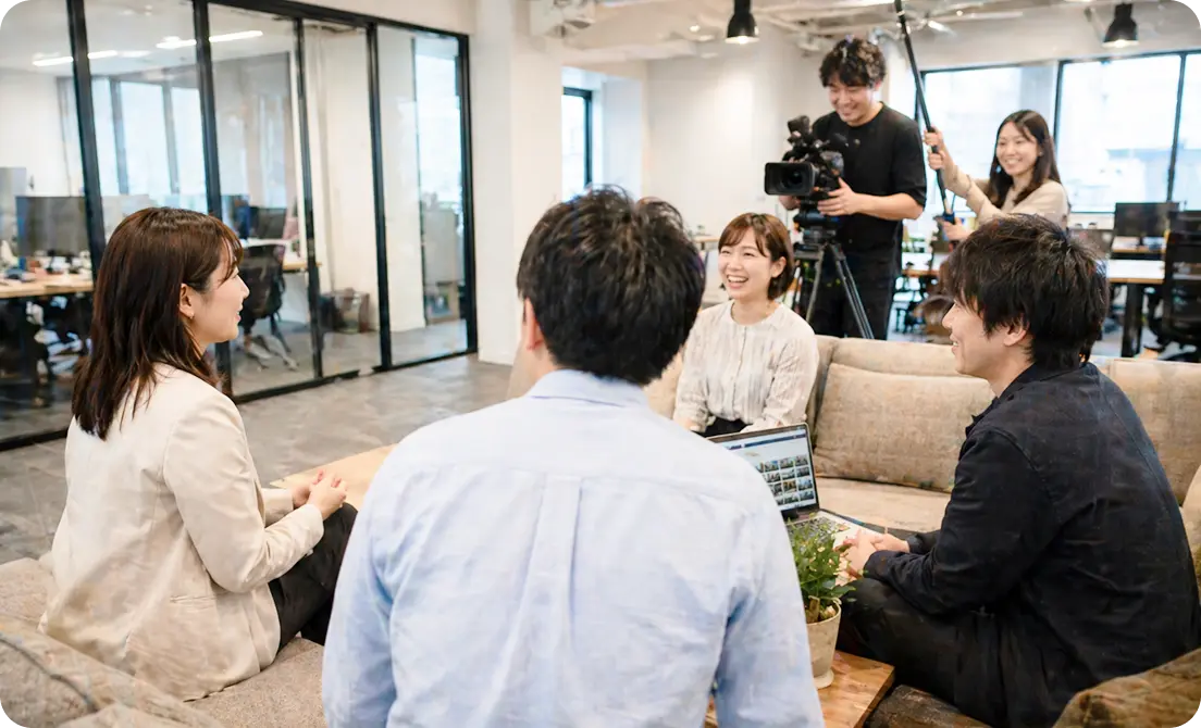 会議室で社員が撮影に参加している様子